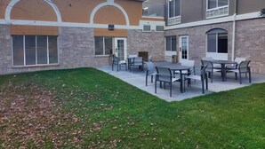 A courtyard with outdoor seating and a brick building with large windows and a door.