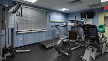 A fitness center with exercise equipment, a treadmill, and a wall-mounted television.