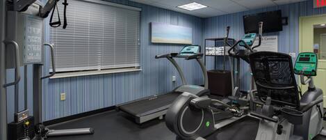 A fitness center with exercise equipment, a treadmill, and a wall-mounted television.