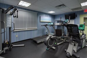 A fitness center with exercise equipment, a treadmill, and a wall-mounted television.