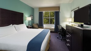 A hotel room with a large bed, a desk with a computer, a TV, and a window with curtains. - Holiday Inn Express Suites Plant City by IHG (Plant City)