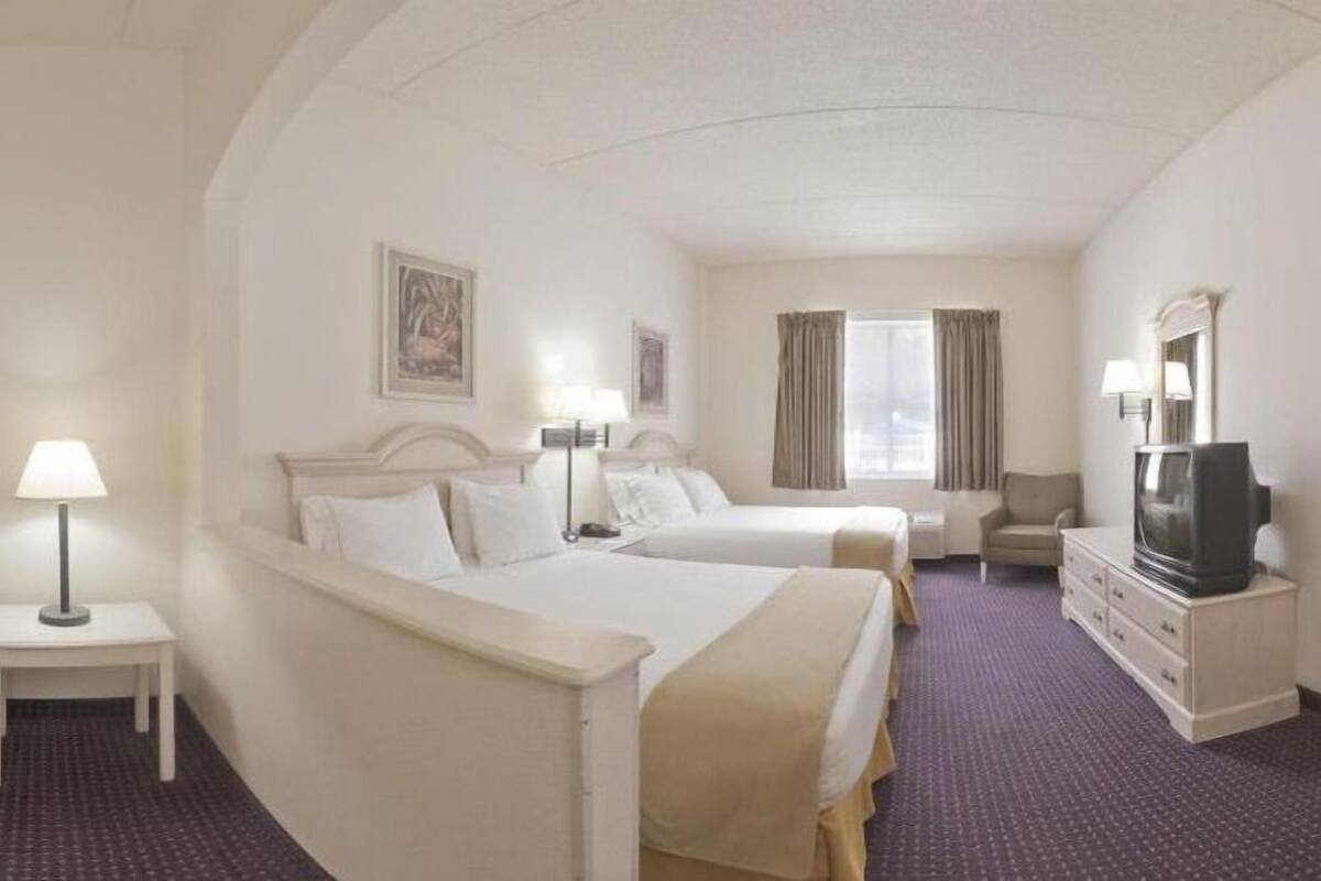 Une chambre d’hôtel avec deux lits, une télévision, un bureau et une chaise.