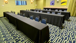 A conference room with long tables and chairs, a patterned carpet, and artwork on the walls. - Holiday Inn Express Suites Plant City by IHG (Plant City)