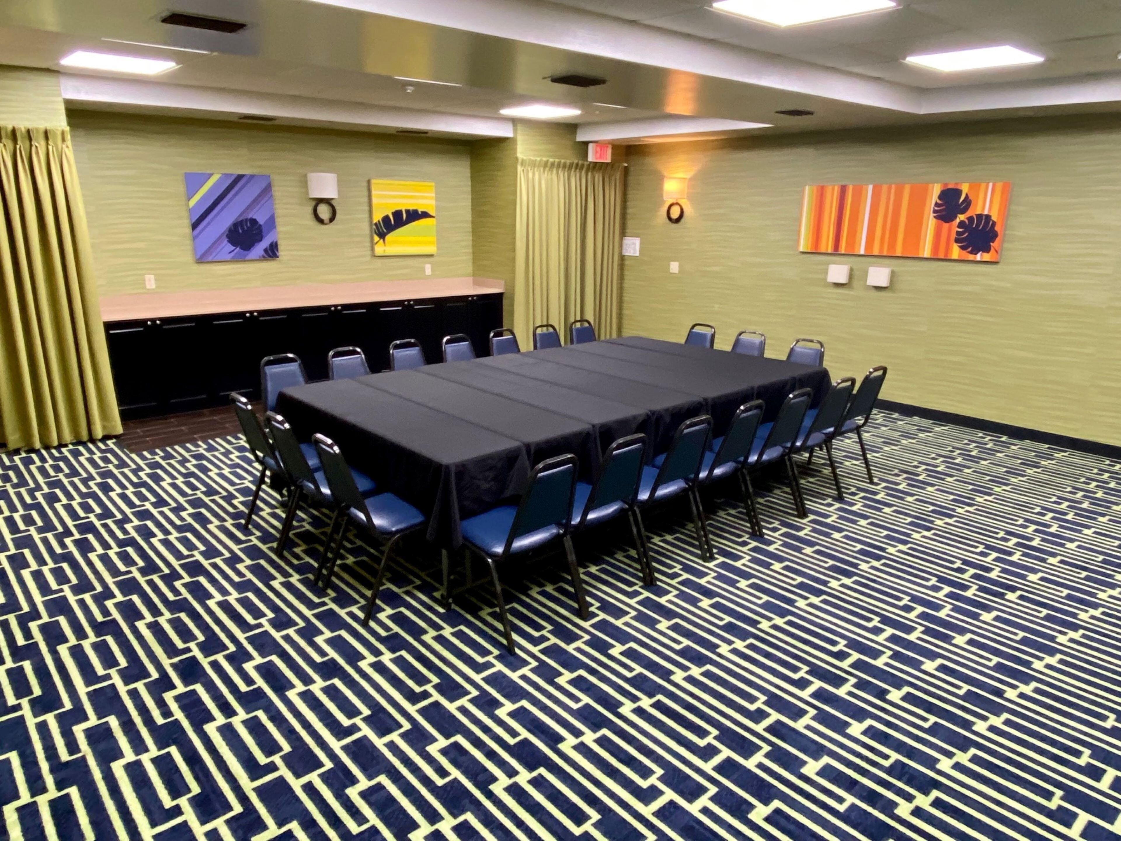 A conference room with a long table, chairs, and a patterned carpet.