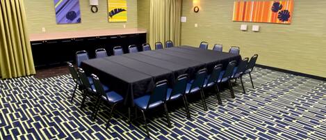 A conference room with a long table, chairs, and a patterned carpet.