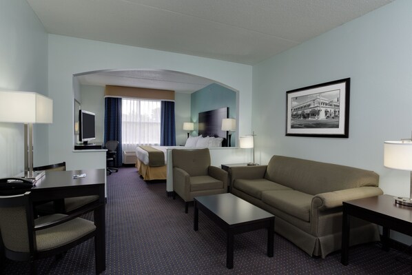 Ein Hotelzimmer mit Bett, Schreibtisch, Sofa und Fernseher.