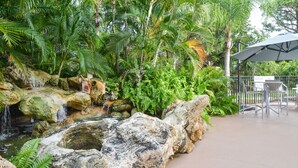 A tropical garden with a waterfall, rocks, and lush greenery. - Holiday Inn Express & Suites Naples North - Bonita Springs by IHG (Bonita Springs)