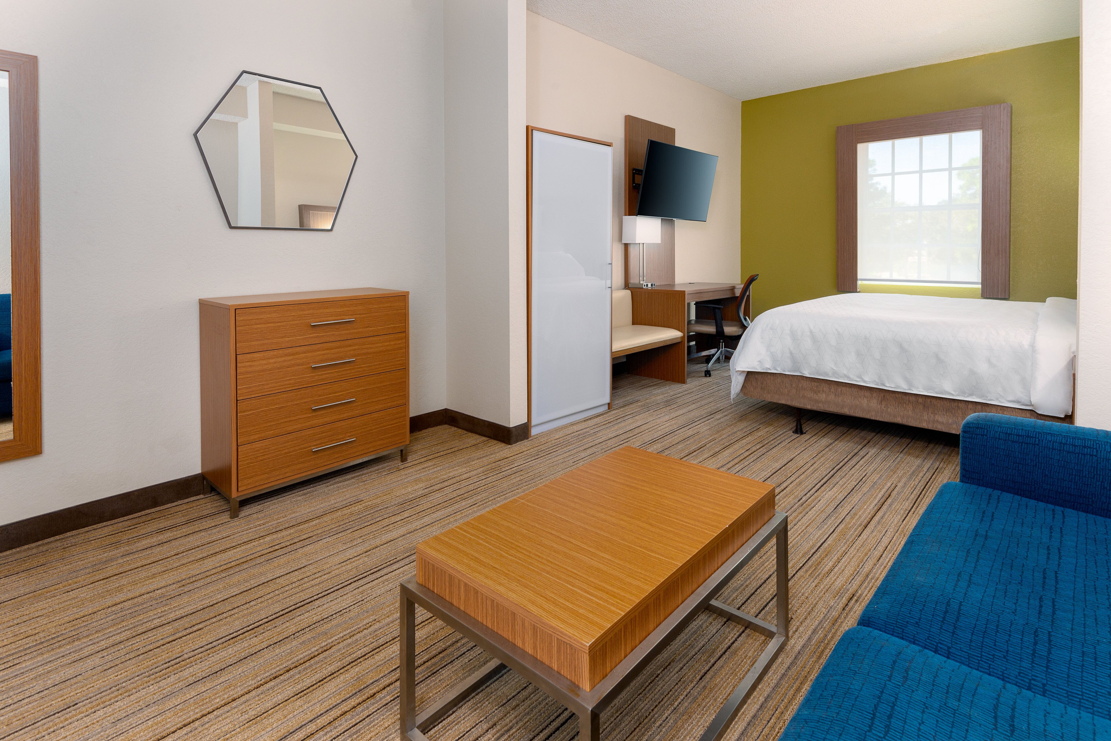 Une chambre d’hôtel équipée d’un lit, d’un bureau, d’une chaise, d’une commode, d’une télévision et d’une fenêtre.