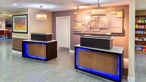 A hotel reception desk with a digital screen, a reception counter, and a wall-mounted television. - Holiday Inn Express & Suites Naples North - Bonita Springs by IHG (Bonita Springs)