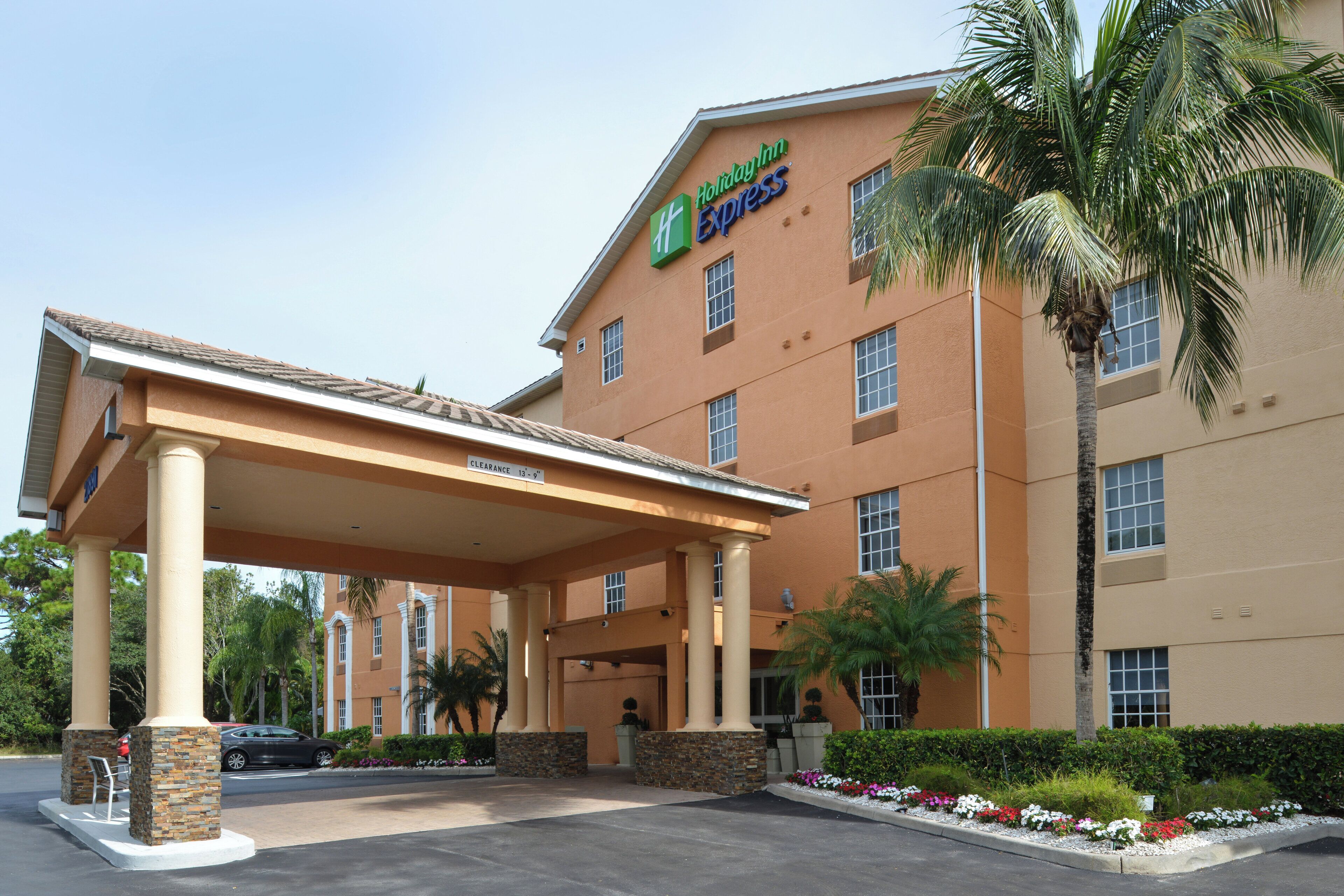 Un bâtiment de l’hôtel Holiday Inn Express doté d’un parking couvert et bordé de palmiers.