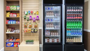 A vending machine with snacks and drinks, a shelf with packaged goods, and a display of small items on the wall. - Holiday Inn Express & Suites Naples North - Bonita Springs by IHG (Bonita Springs)