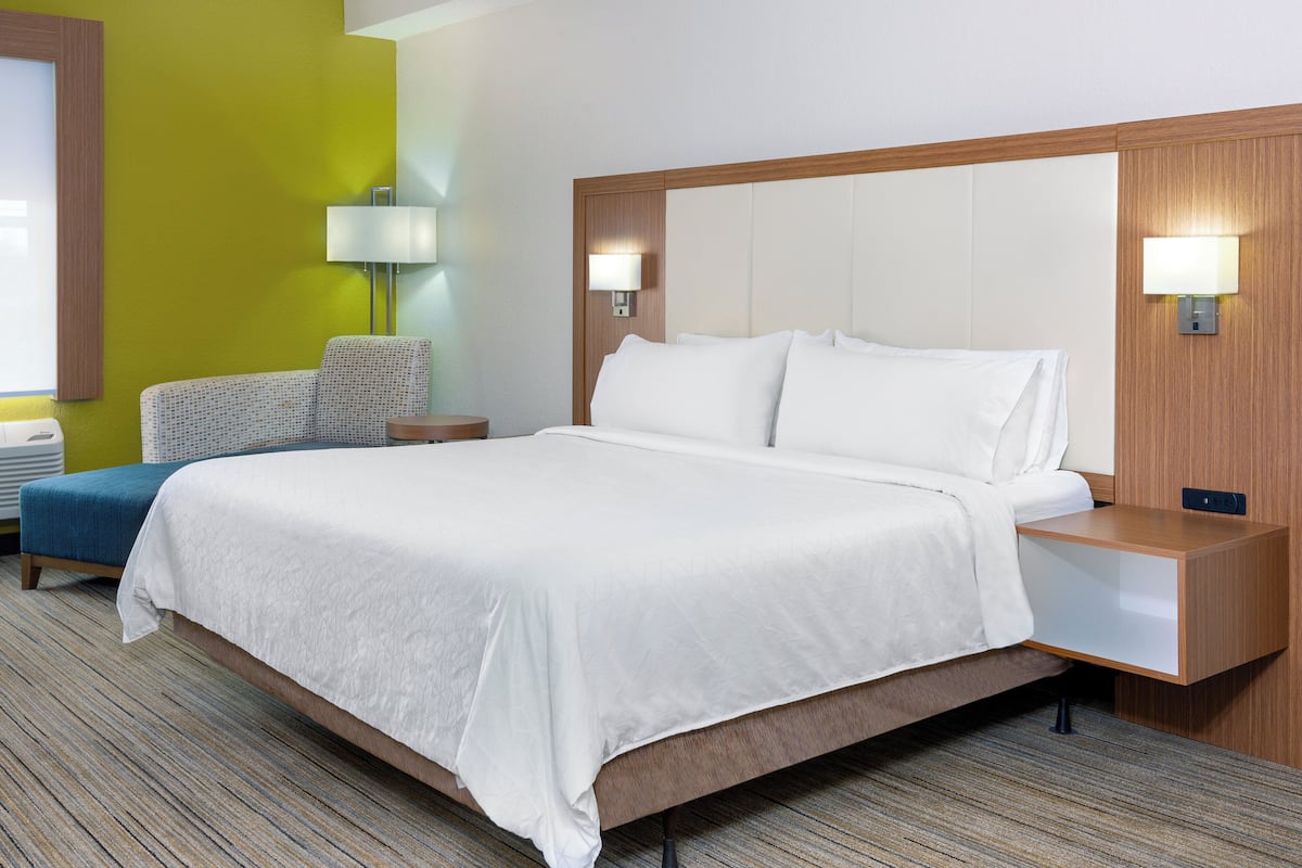 Ein Hotelzimmer mit einem großen Bett, Nachttischen, einer Lampe und einem Sessel.