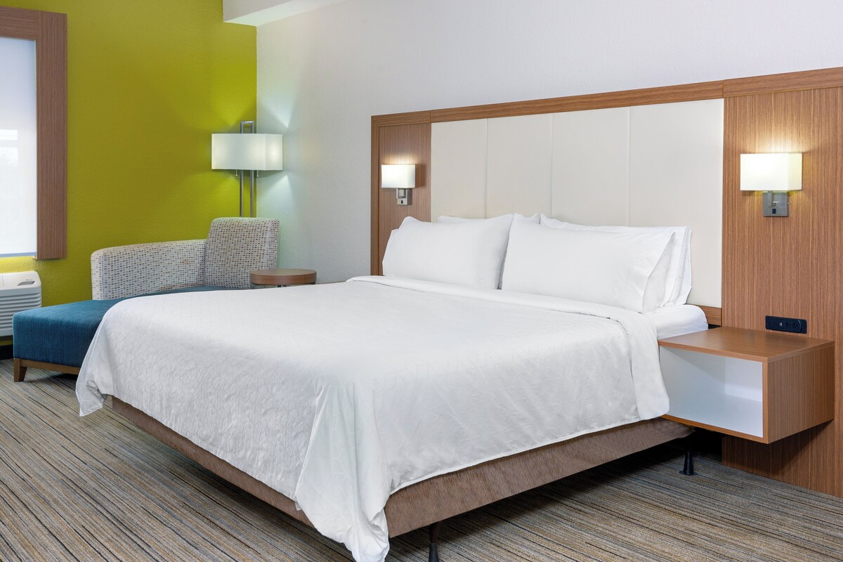 Ein Hotelzimmer mit einem großen Bett, Nachttischen, einer Lampe und einem Sessel.