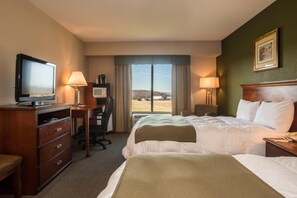 A hotel room with a bed, desk, television, and a view of the outdoors.