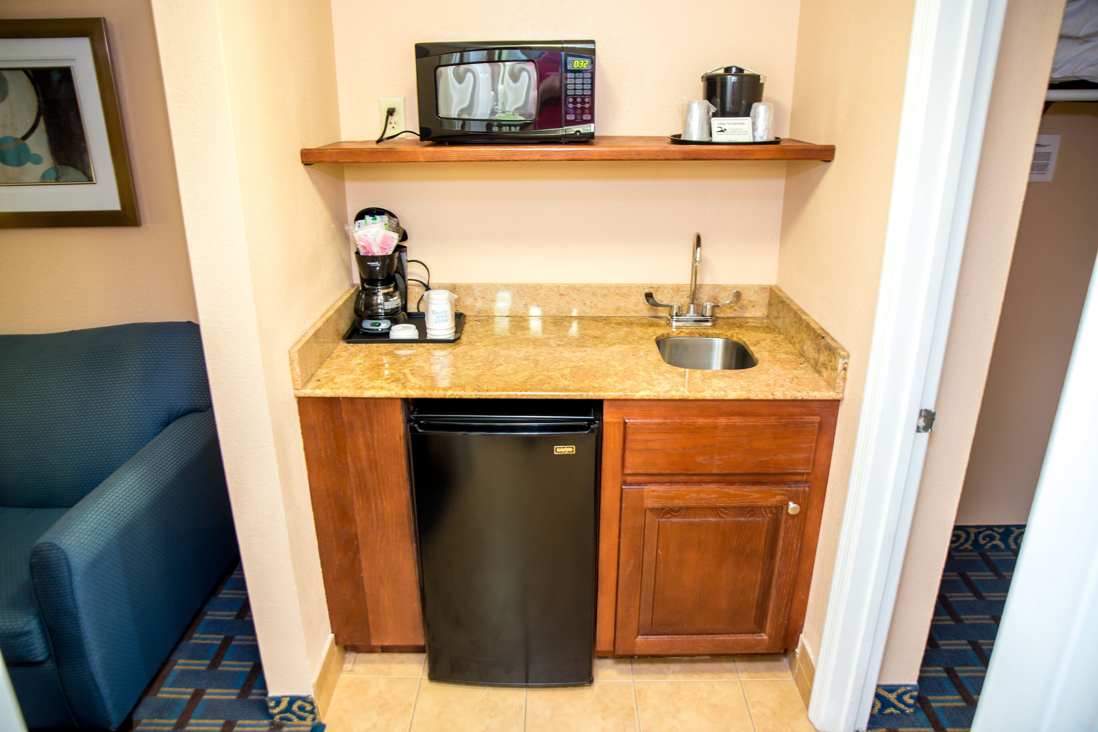 A compact kitchenette with a microwave, coffee maker, and dishwasher.