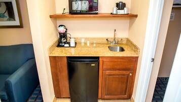 A compact kitchenette with a microwave, coffee maker, and dishwasher.
