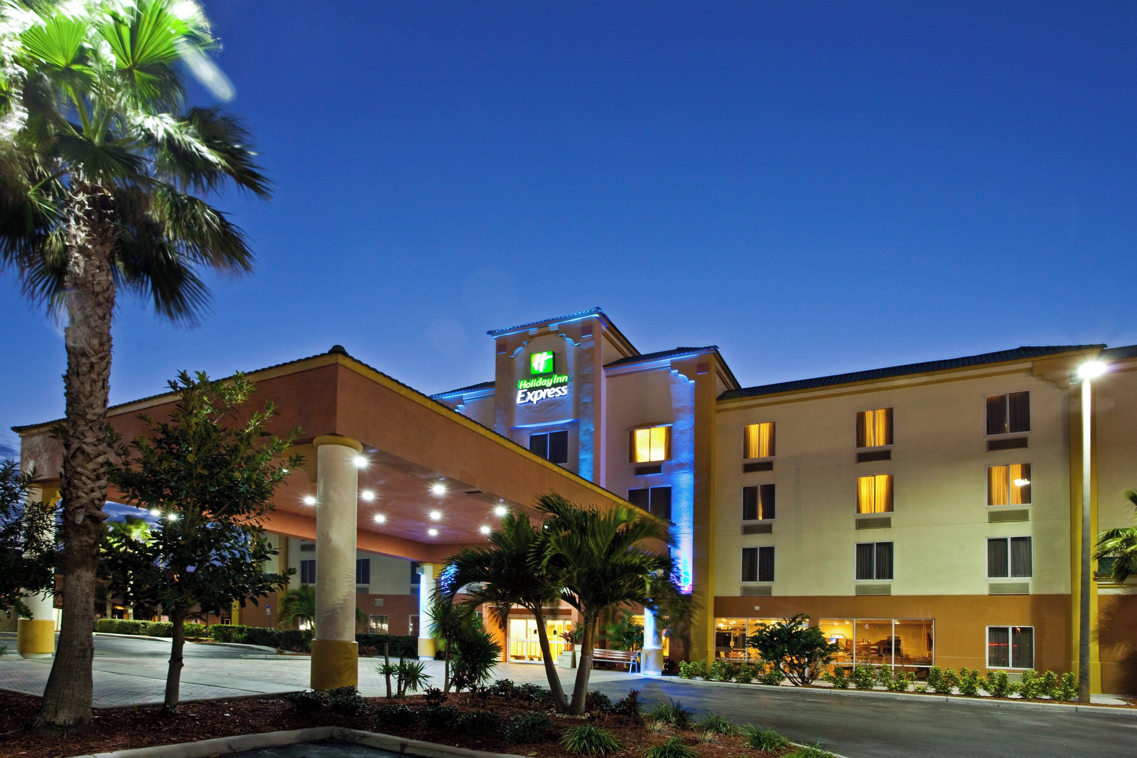 Un hotel Holiday Inn Express con diseño moderno, que destaca por su cartel llamativo, varios pisos y una entrada bien iluminada.