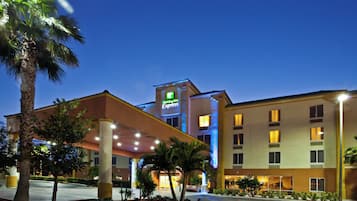 Un hotel Holiday Inn Express con diseño moderno, que destaca por su cartel llamativo, varios pisos y una entrada bien iluminada.