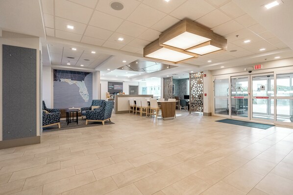 A spacious lobby with a reception desk, seating area with chairs, and a large map on the wall. - Holiday Inn Express Hotels & Suites Cocoa Beach by IHG (Cocoa Beach)