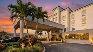 A hotel with a covered entrance, palm trees, and a sunset sky. - Holiday Inn Express Hotels & Suites Cocoa Beach by IHG (Cocoa Beach)