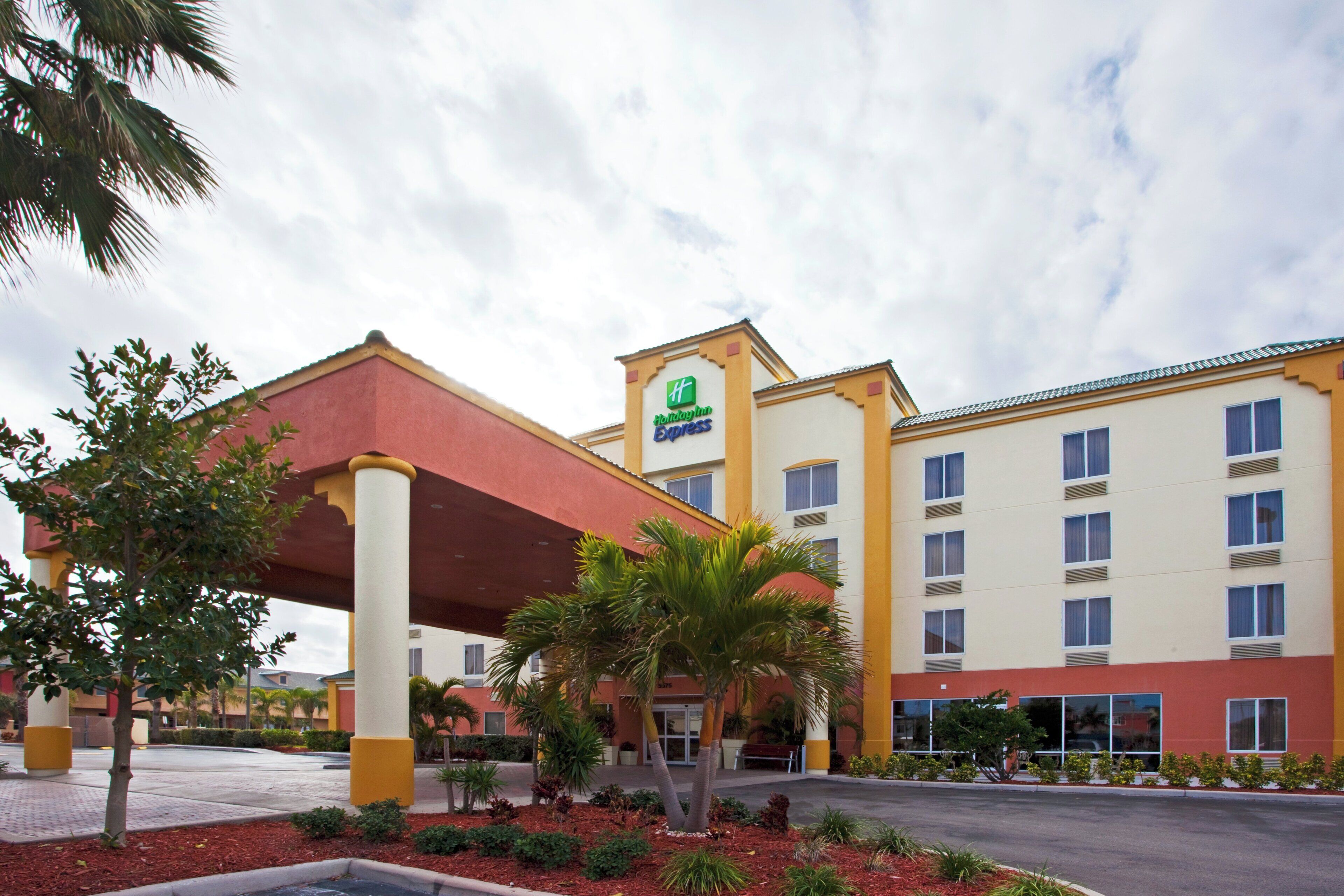 Um hotel Holiday Inn Express com entrada coberta, vários andares e estacionamento.