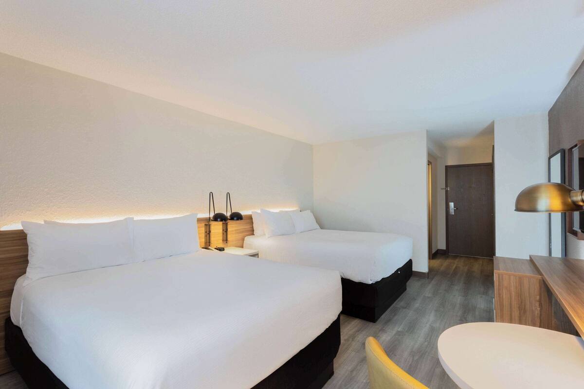 Une chambre d’hôtel avec deux lits, un bureau et une chaise.