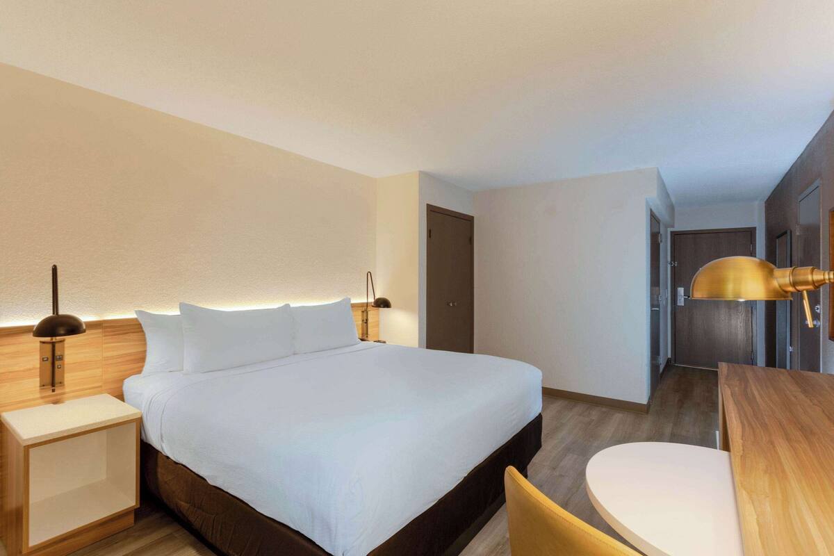 Une chambre d’hôtel avec un grand lit, des tables de chevet, un bureau et une chaise.