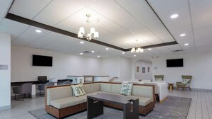 A modern hotel lobby with a sectional sofa, a coffee table, and a reception desk.