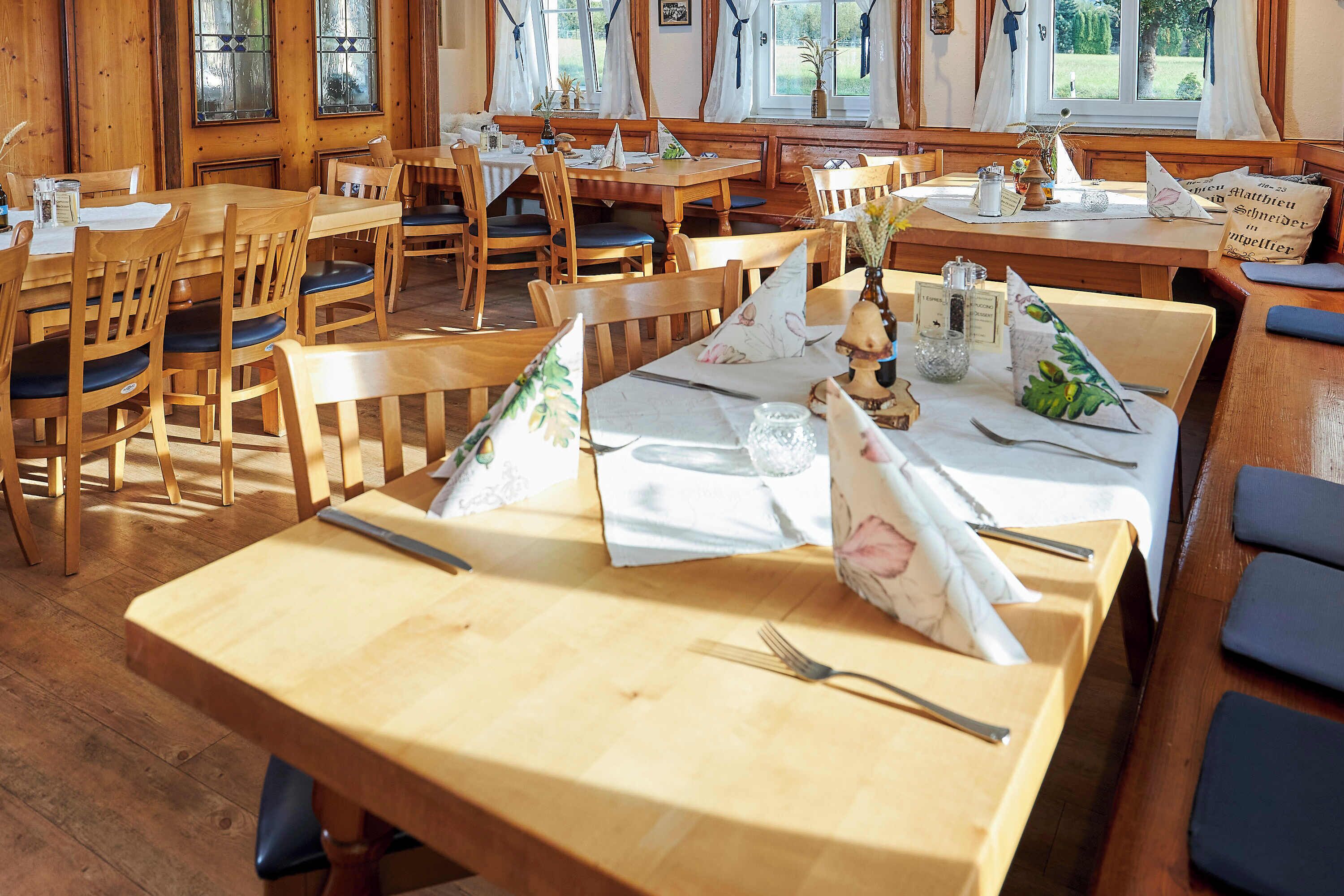 En restaurant med træmøbler og dækketøjsdækkede borde.