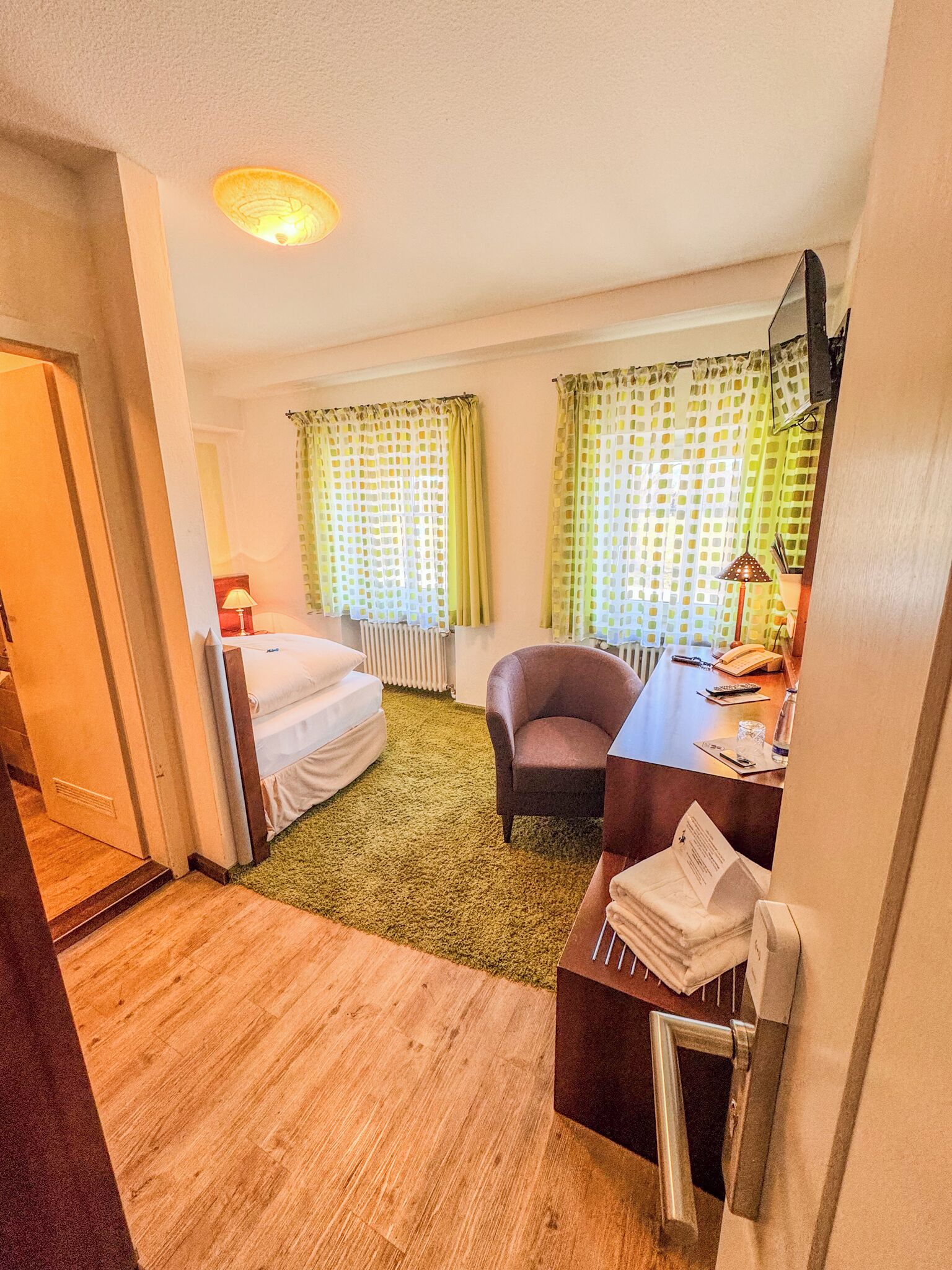 Ein Hotelzimmer mit Bett, Schreibtisch, Stuhl und Heizkörper.