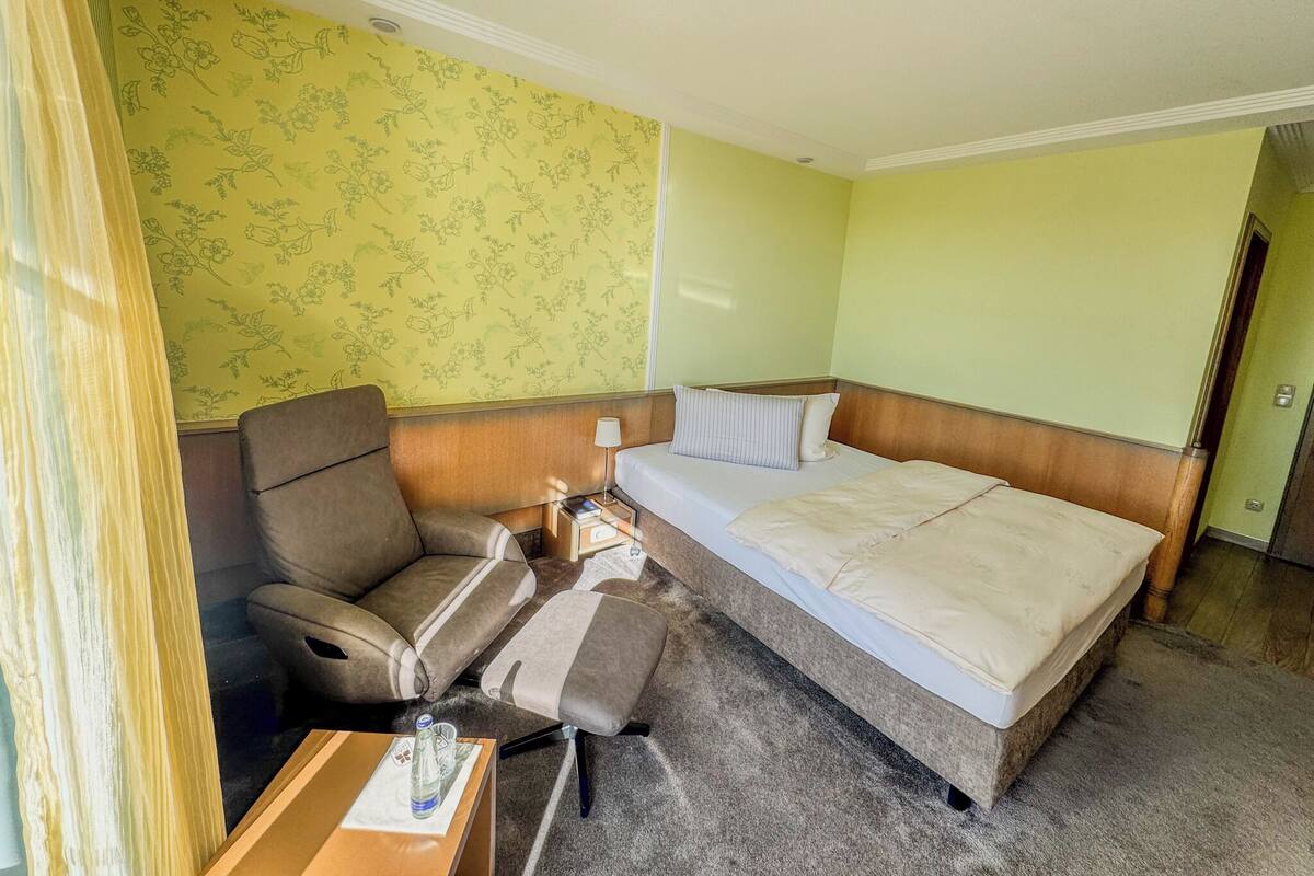 A hotel room with a bed, a sofa, a small table, and a chair.