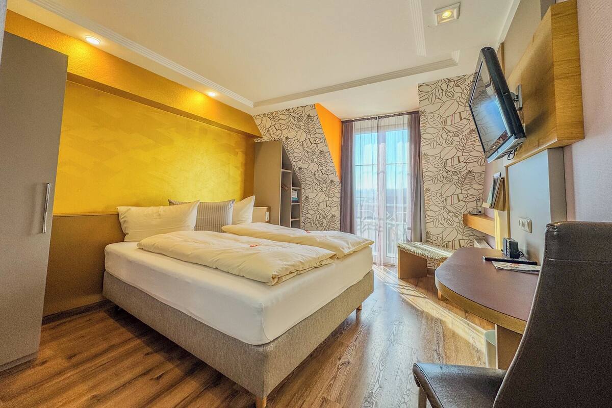 A modern hotel room with a large bed, a desk, and a television.