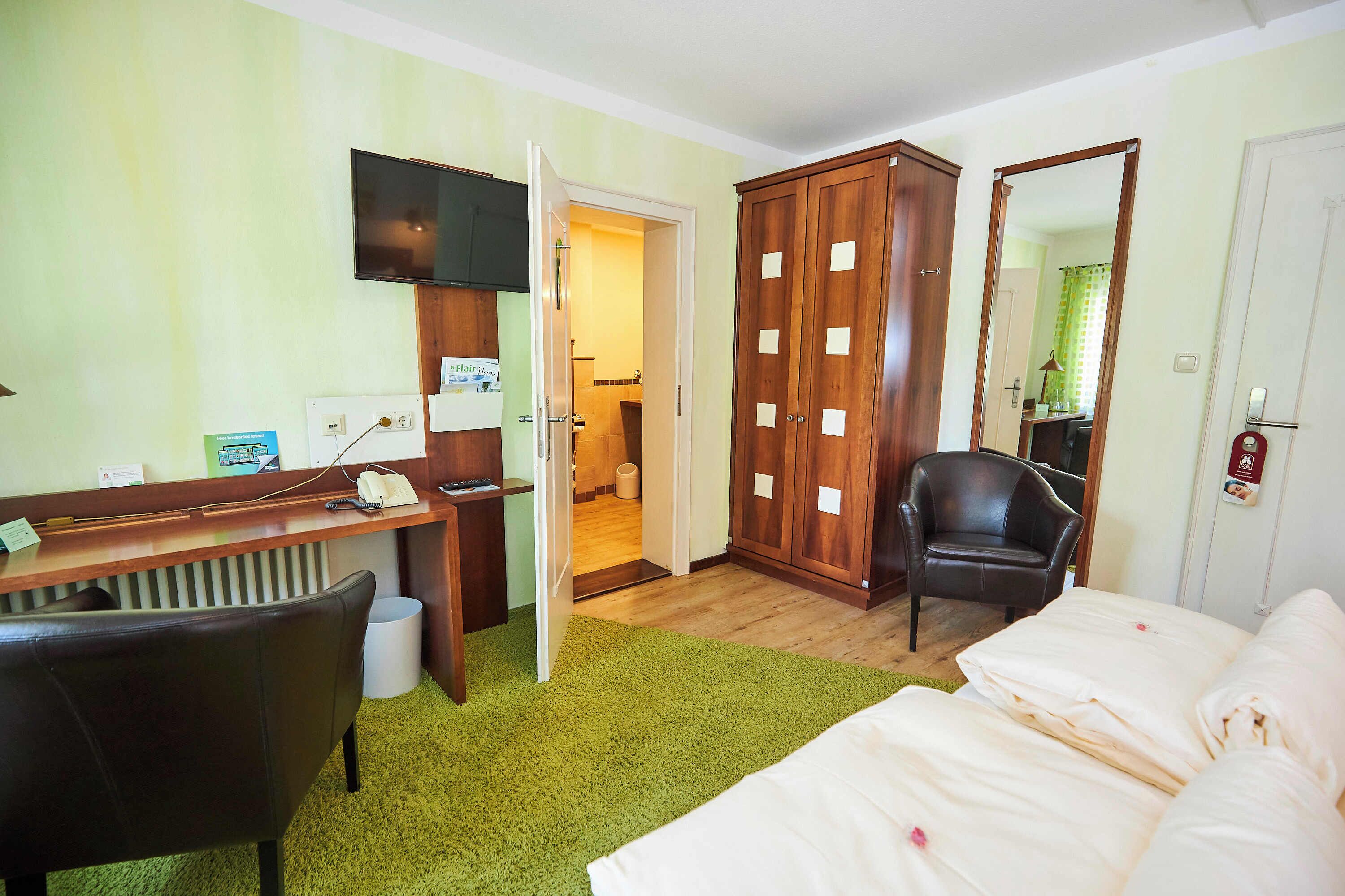 Une chambre d’hôtel équipée d’un lit, d’un bureau, d’une chaise, d’une armoire et d’un téléviseur.