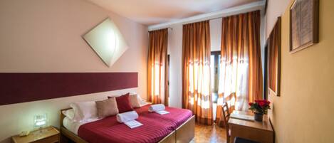 Una habitación de hotel con cama, mesita de noche, escritorio, silla y maleta.
