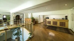 A spacious lobby with a reception desk, a staircase with a glass railing, and a wooden floor. - Hotel La Vecchia Cartiera (Colle di Val d'Elsa)