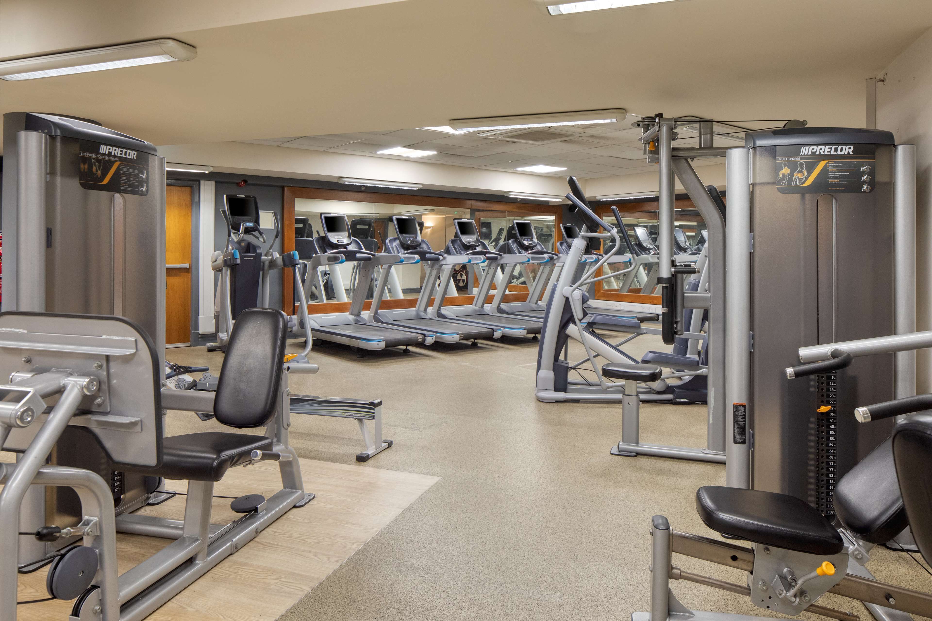 A gym with treadmills, weight machines, and a mirrored wall.
