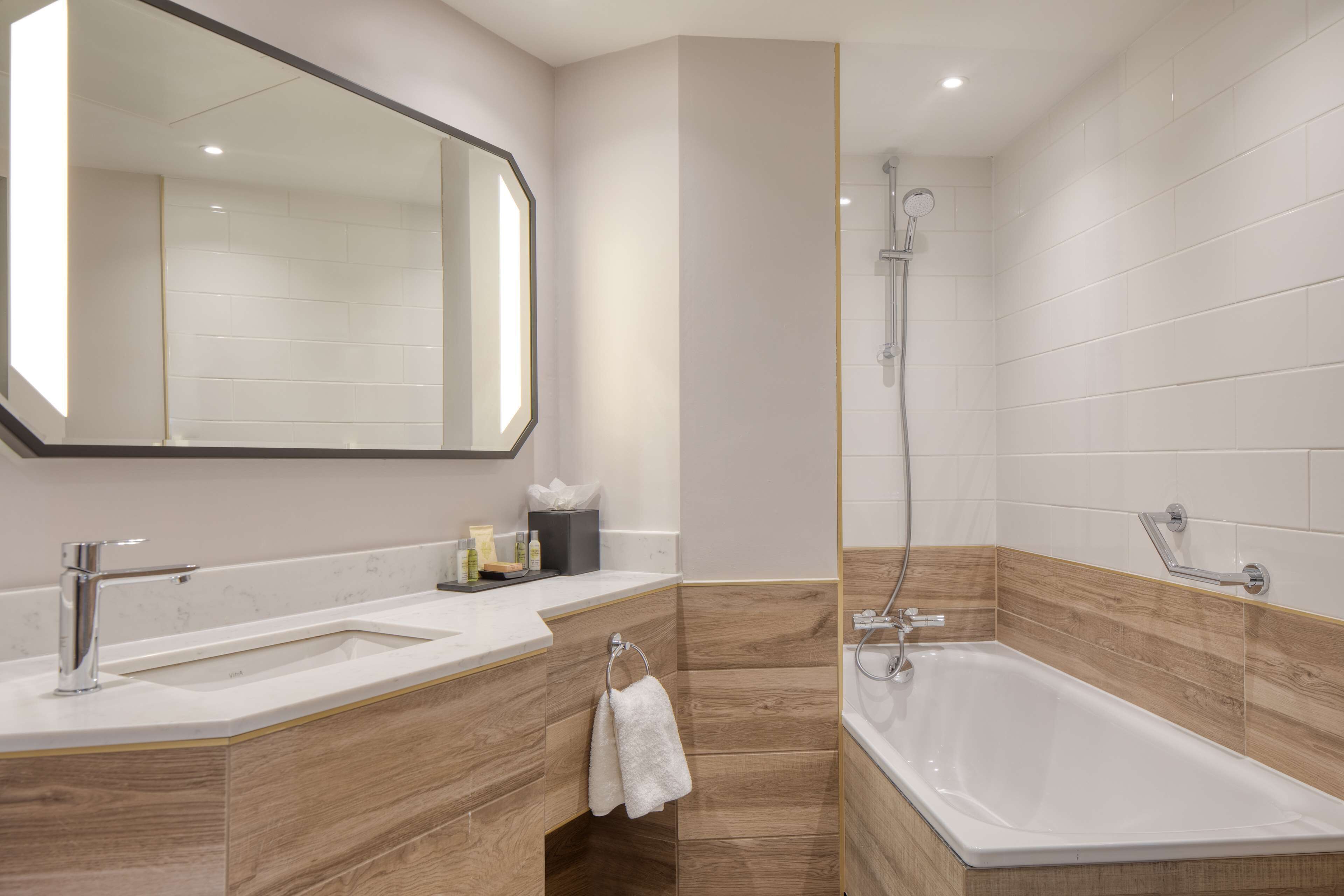 Un bagno moderno con due lavabi, uno specchio ampio, una doccia e una vasca.