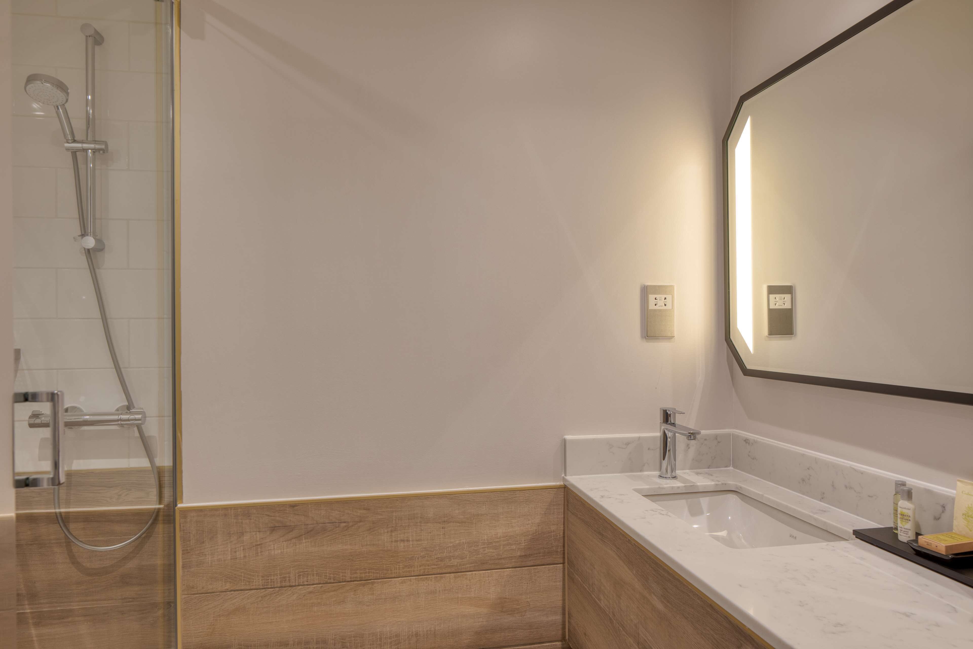 Une salle de bain moderne avec une douche, un lavabo et un miroir.