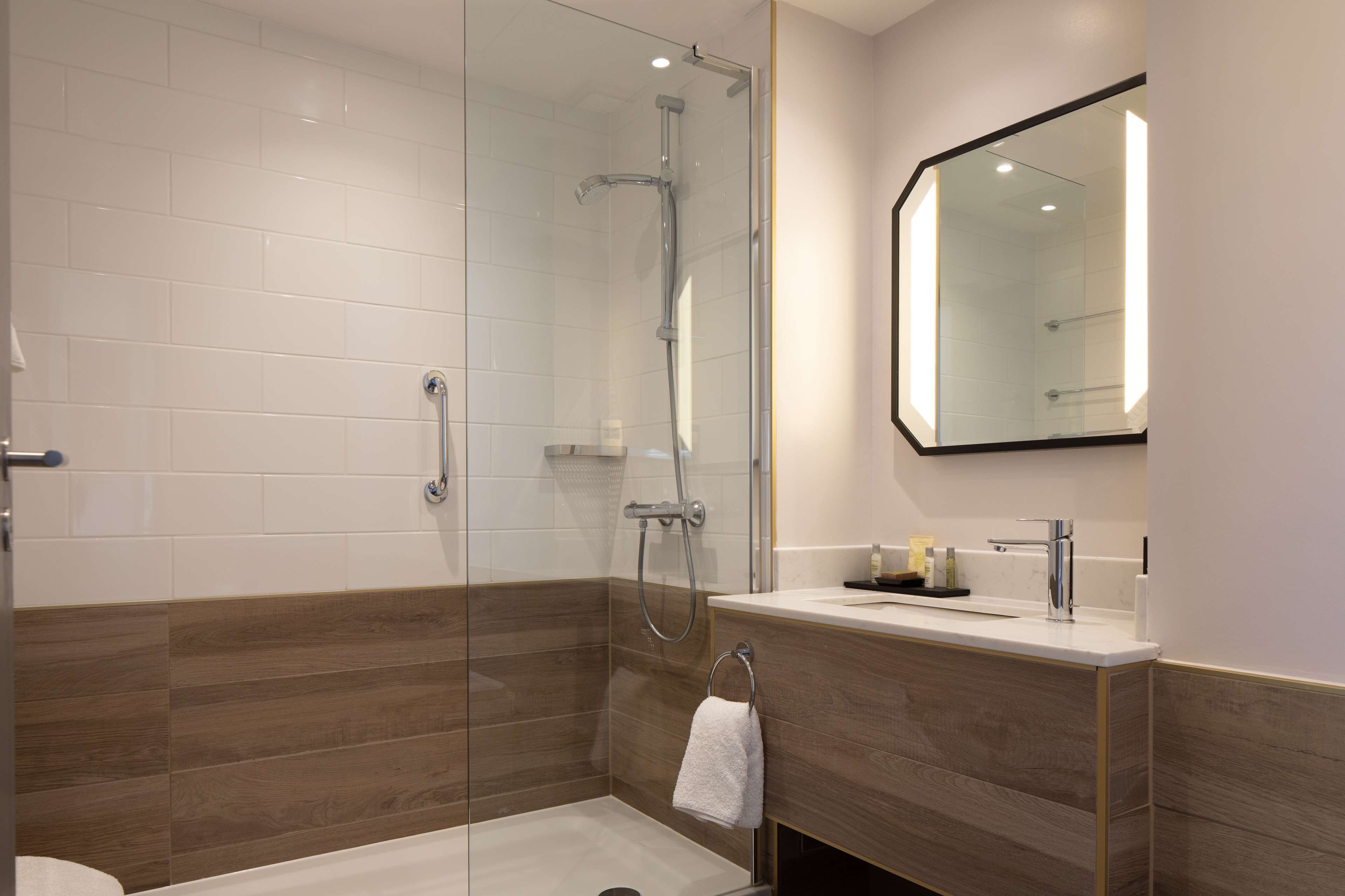 Un bagno moderno con cabina doccia in vetro, un mobile bagno in legno e uno specchio grande.
