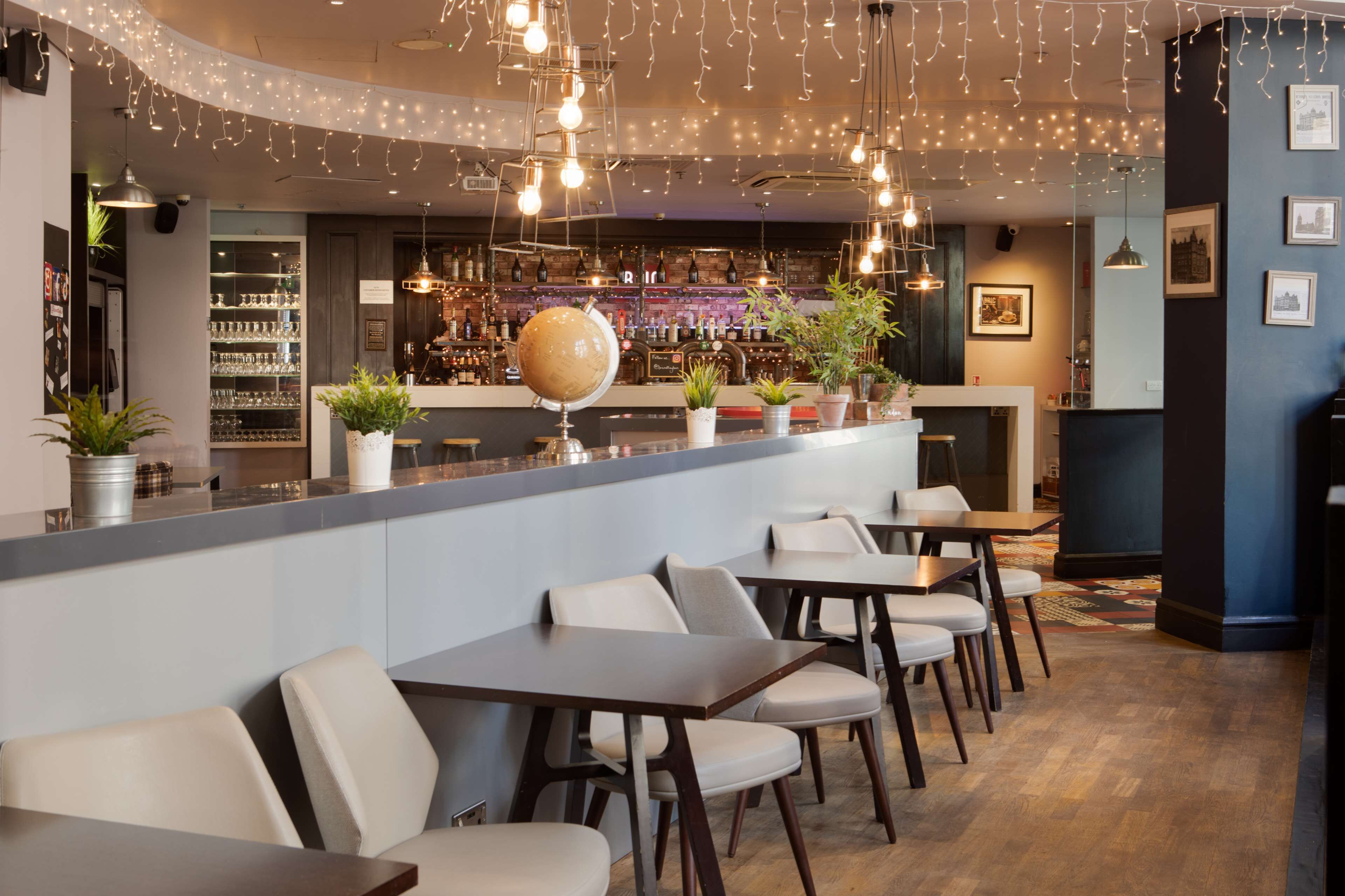 A bar area with a globe decoration, potted plants, and a variety of bottles on shelves.