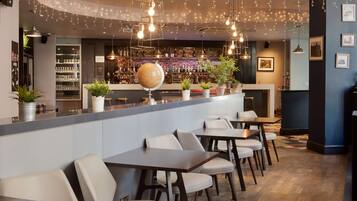Una zona de bar con un globo decorativo, plantas en macetas y una variedad de botellas en estanterías.
