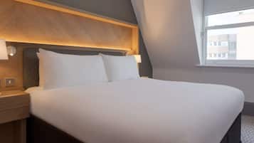 A neatly made bed with white linens, a wooden headboard, and bedside lamps.