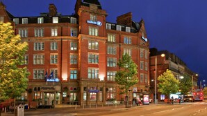 Un hotel grande e histórico con varias plantas y una ubicación destacada en una esquina.