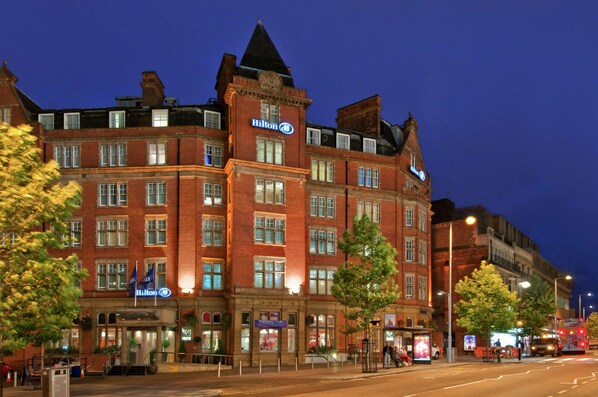 Un hotel grande e histórico con varias plantas y una ubicación destacada en una esquina.