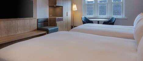 Ein Hotelzimmer mit zwei Betten, einem Fernseher, einem Schreibtisch und einem Stuhl.