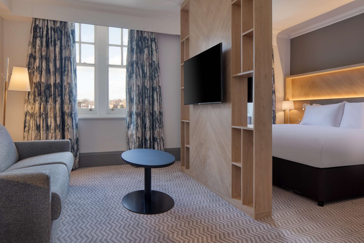 A hotel room with a bed, a sofa, a television, and a small table.