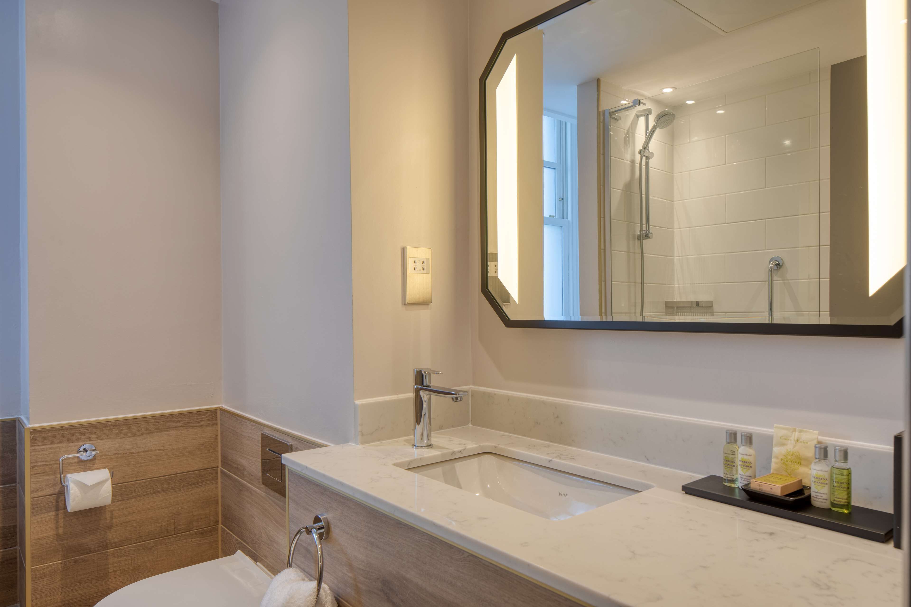 Une salle de bain moderne avec un grand miroir, un lavabo et une douche.