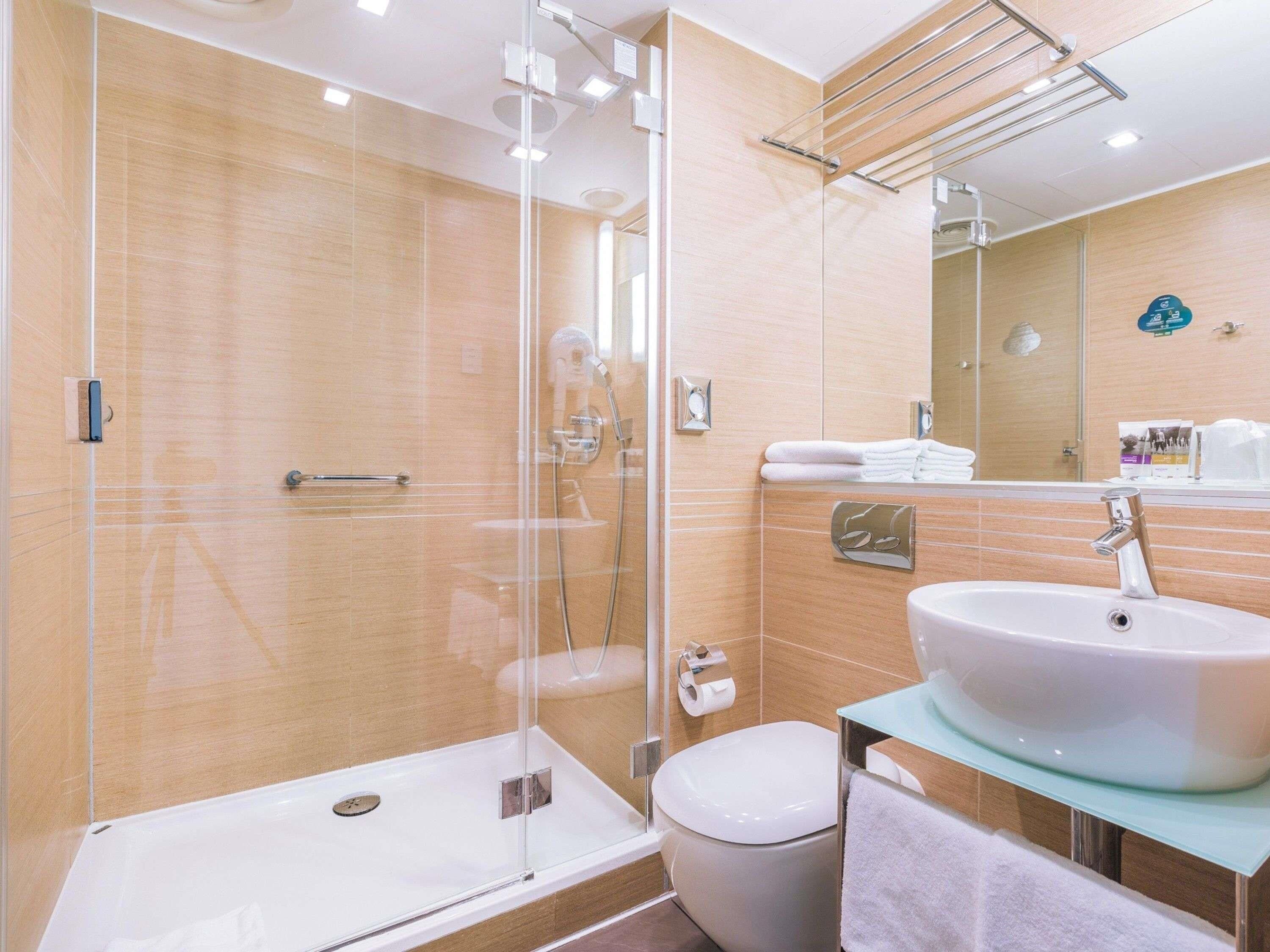 Un baño moderno con ducha de vidrio, lavamanos blanco y retrete.