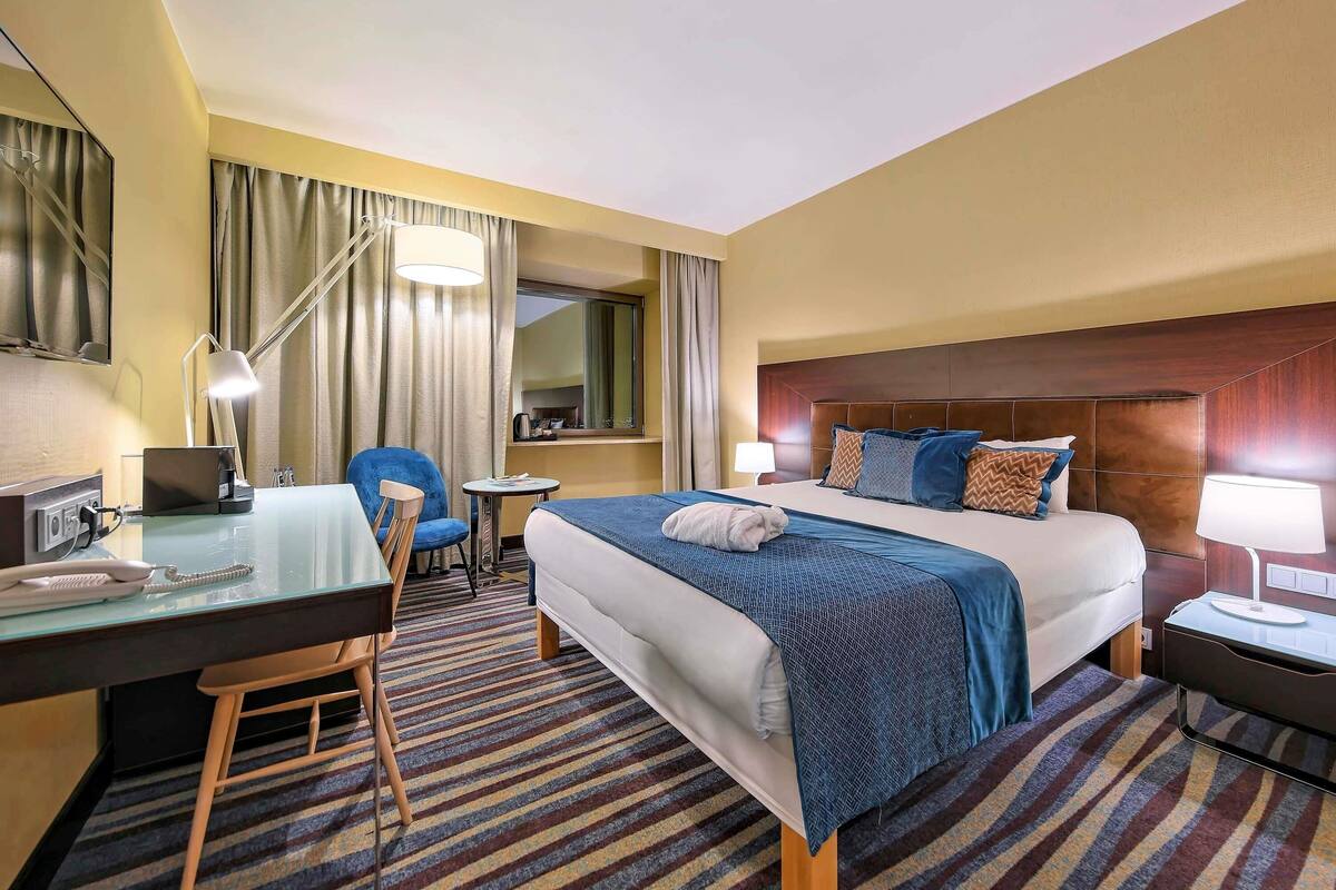 Una habitación de hotel con cama, escritorio, silla y una pequeña mesa.