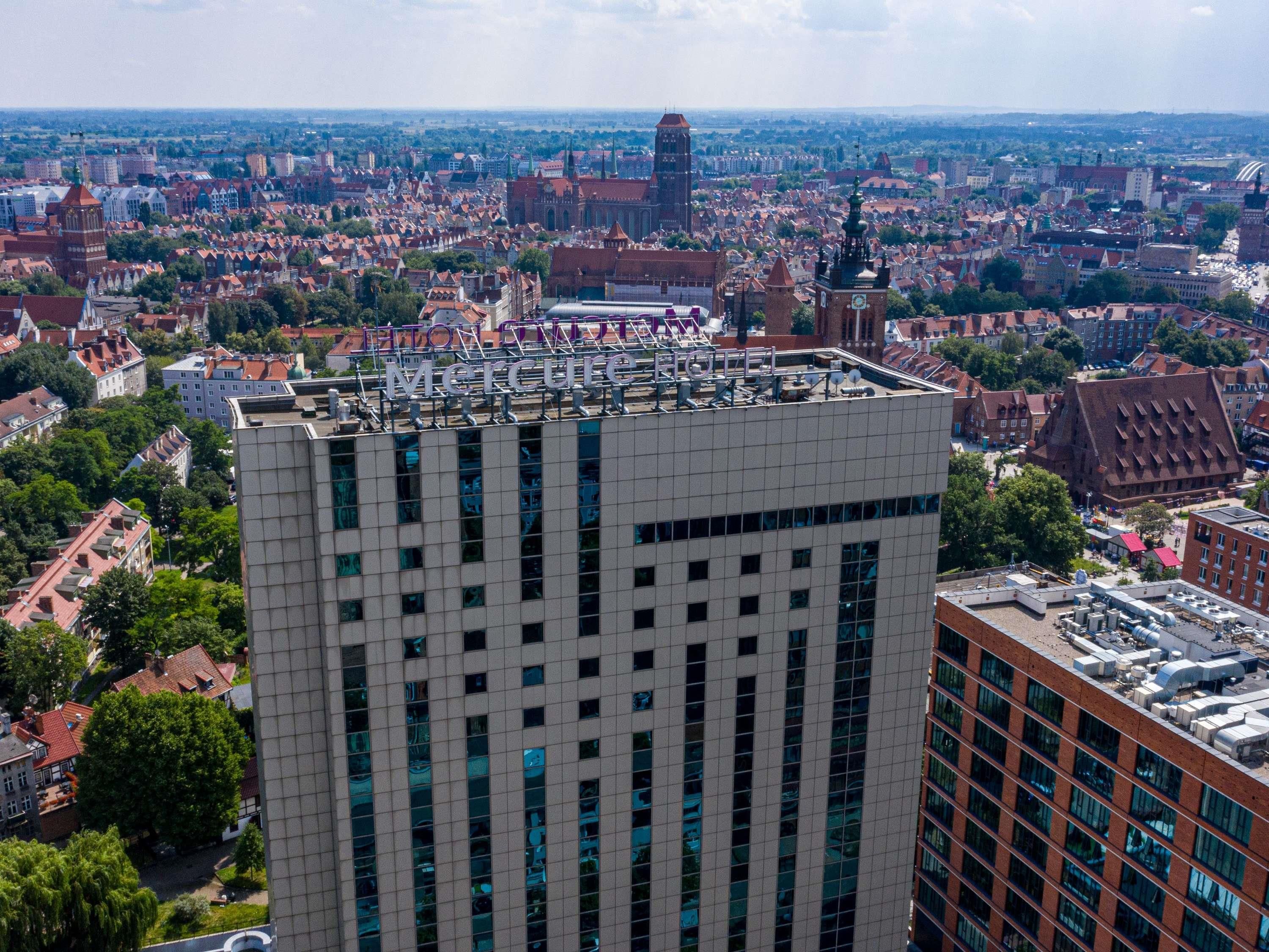 A high-rise hotel with a modern facade, large windows, and a rooftop terrace.